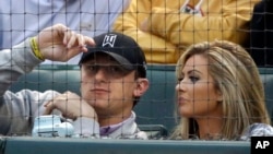 FILE - Cleveland Browns quarterback Johnny Manziel, left, sits with Colleen Crowley during a baseball game in Arlington, Texas, April 14, 2015.