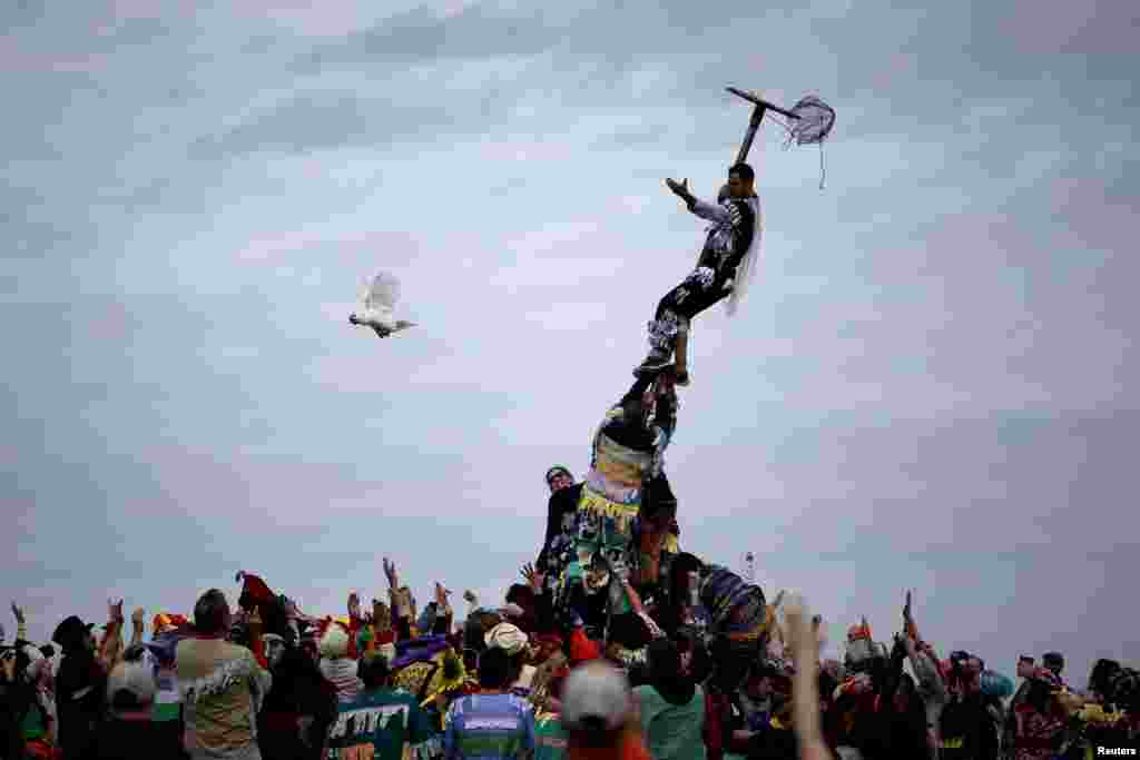 A reveler releases a chicken from a cage after climbing a greased pole during the Faquetaique Courir de Mardi Gras celebration in Eunice, Louisiana, Feb. 13, 2018.