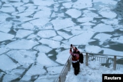 A pedestrian stops to take a photo by Chicago River, as bitter cold phenomenon called the polar vortex descends on much of the central and eastern United States, in Chicago, Jan. 29, 2019.