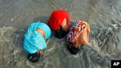 Female Hindu pilgrims take a dip at the confluence of the Ganges river and the Bay of Bengal at Sagar Island, India, January 13, 2012. (Reuters)