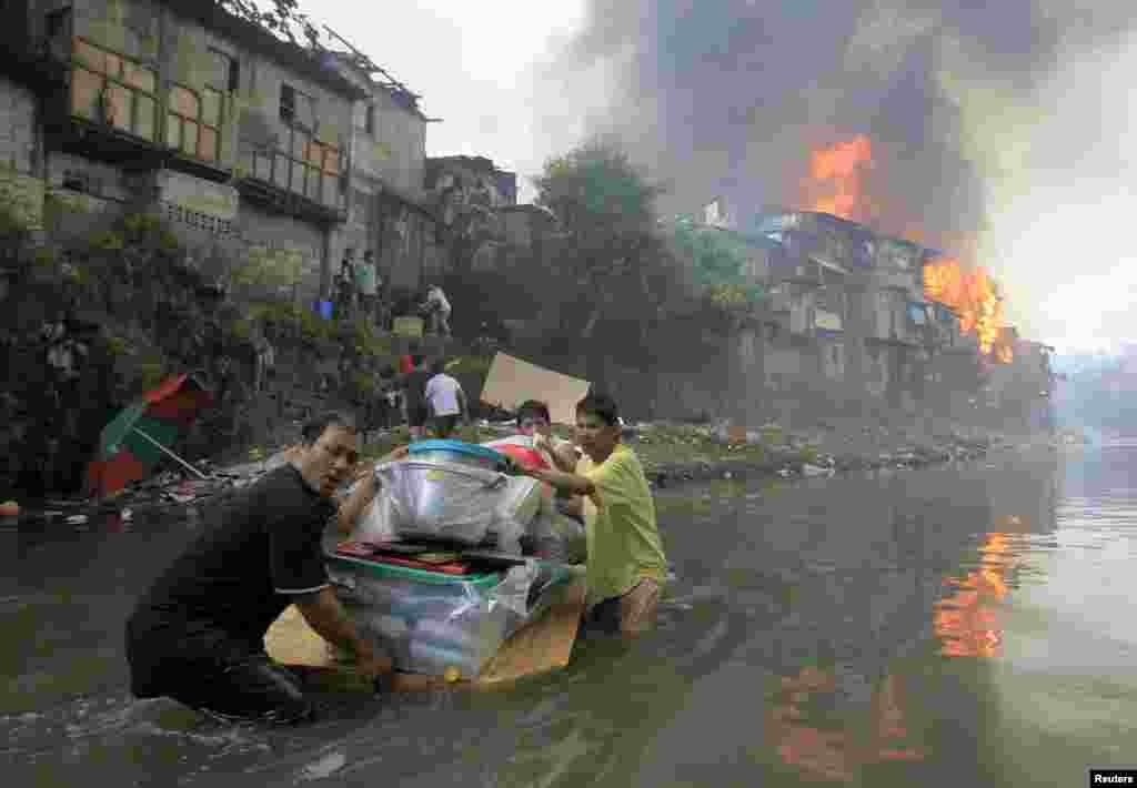 Warga berupaya menyelamatkan barang-barang miliknya saat kebakaran membumi hanguskan sekitar 2.000 rumah di Quezon city, Manila, Filipina.