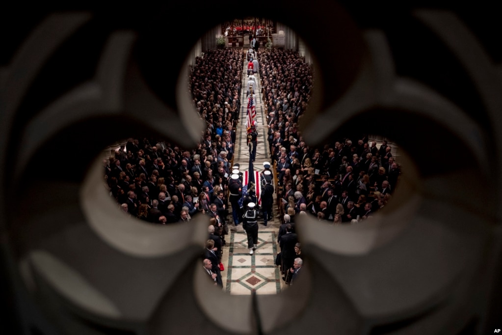 The flag-draped casket of former President George H.W. Bush is carried by a military honor guard into a State Funeral at the National Cathedral, Dec. 5, 2018, in Washington.