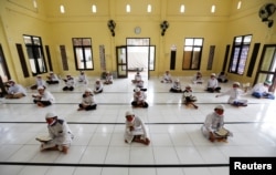 Para siswa Muslim membaca al-Quran dengan memakai masker dan menjaga jarak aman di sebuah pesantren di Bogor, Jawa Barat, sebagai ilustrasi. (Foto: Reuters).