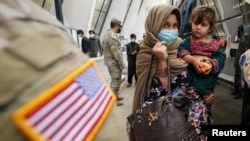 FILE - Afghan refugees board a bus taking them to a processing center upon their arrival at Dulles International Airport in Dulles, Virginia, Sept. 1, 2021. 