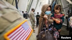 FILE - Afghan refugees board a bus taking them to a processing center upon their arrival at Dulles International Airport in Dulles, Virginia, Sept. 1, 2021.