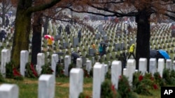 Volunteers help to lay holiday wreaths at graves at Arlington National Cemetery in Arlington, Va., Dec. 15, 2018, during Wreaths Across America Day.