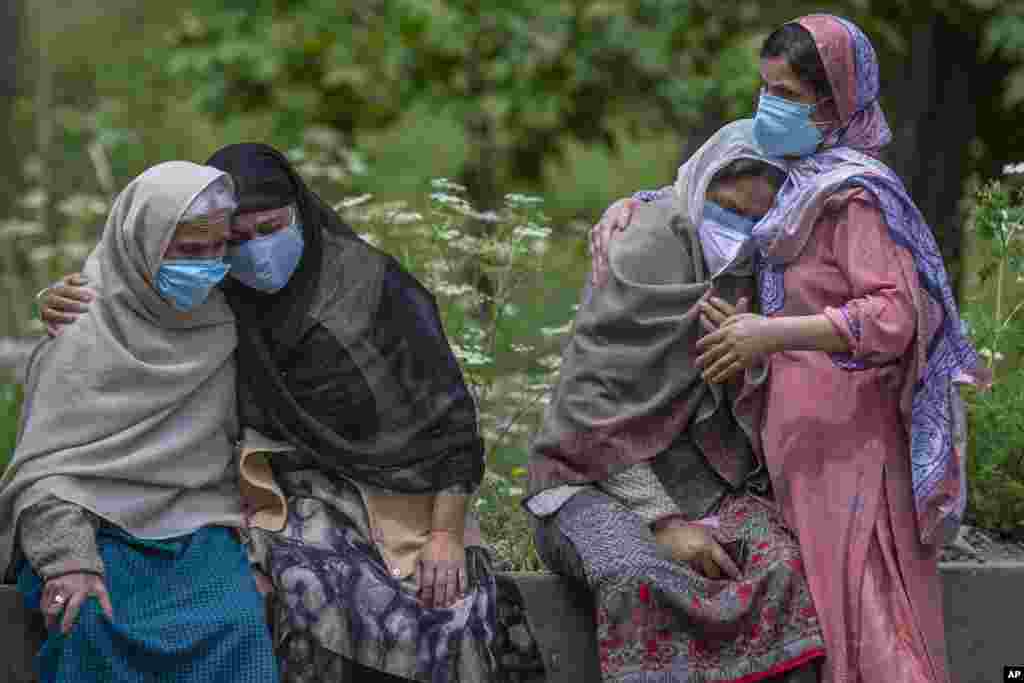 Women comfort family members of a person who died of COVID-19 at a crematorium in Srinagar, Indian-controlled Kashmir.