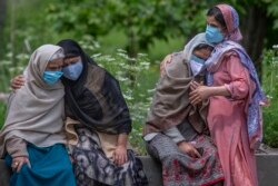 Wanita tak dikenal menghibur anggota keluarga seseorang yang meninggal karena COVID-19, di sebuah krematorium di Srinagar, Kashmir, Selasa, 25 Mei 2021. (Foto: AP)