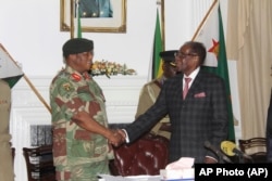 FILE: Zimbabwean President Robert Mugabe, right, shakes hands with Army General Constantino Chiwenga before delivering his speech during a live broadcast at State House in Harare, Sunday, Nov, 19, 2017.