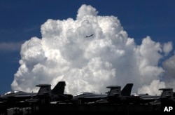 A commercial plane flies over the USS Ronald Reagan aircraft carrier in Hong Kong, Monday, Oct. 2, 2017.