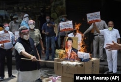 2020年6月的中印邊境衝突後，在印度新德里舉行的一次抗議活動中，印度商人焚燒中國商品和中國國家主席習近平的海報。（2020年6月22日）