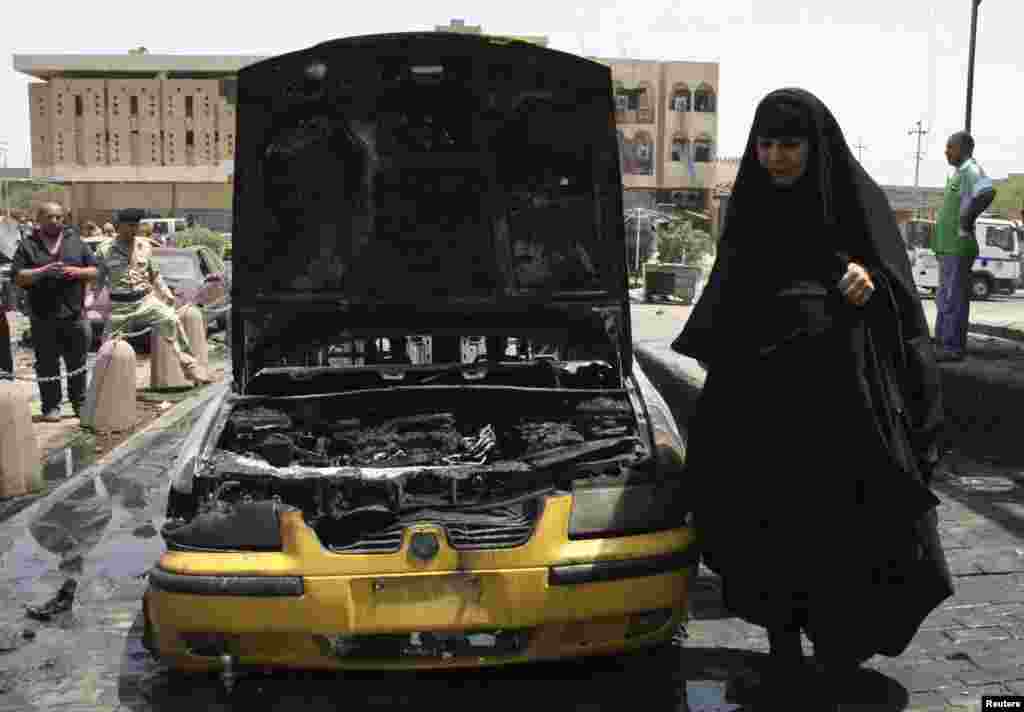 A woman walks at the site of car bomb attack in Sadr city, northeastern Baghdad, Iraq, July 23, 2012.