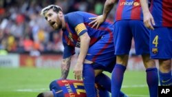 Lionel Messi s’incline pour assister son coéquipier Neymar du FC Barcelone, à gauche, touché par un projectile jeté par un spectateur lors du match de la Liga espagnole de football entre Valence et le FC Barcelone au stade Mestalla à Valence, Espagne, 22 octobre 2015.