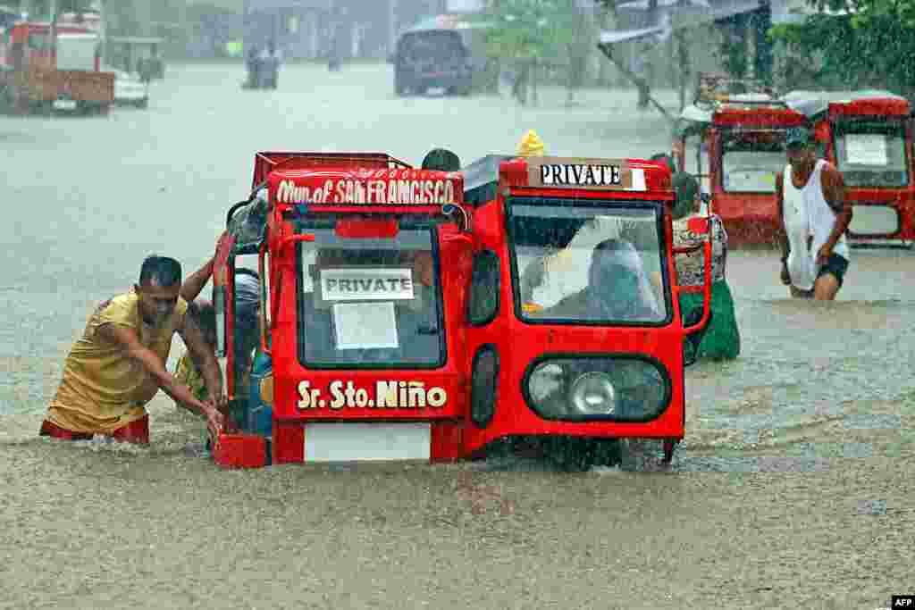 People push a half-underwater tricycle through a flooded street due to heavy rains caused by tropical depression Vicky in San Francisco town, Agusan del sur province on the southern island of Mindanao, Philippines.