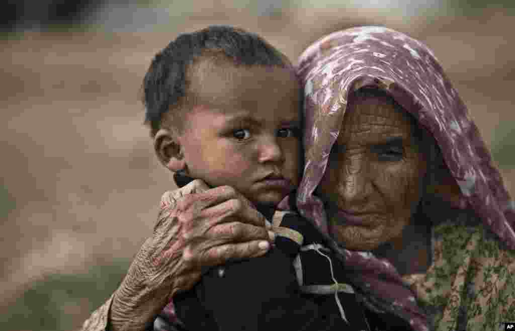 The young and the old - Elderly Pakistani, Nouran Nazir, 83, holds her 18-month-old grandson Sayyim, next to the rubble of her makeshift home, which was destroyed along with other homes by the Capital Development Authority for being built on illegal lands, in Islamabad.