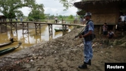 FILE - A Myanmar border guard police officer stands guard in Taung Bazar village, Buthidaung township, northern Rakhine state, Myanmar, July 13, 2017.