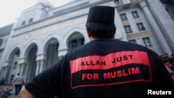 یکی از مسلمانان مالزی که در بیرون از ساختمان دادگاه در پوتراجایا، در حومه کوالالامپور، ایستاده است. ۲ تیر ۱۳۹۳ 