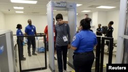 FILE - Autistic boy Jeffery Jr. Simonton (C) walks through the metal detector while a Transportation Security Administration (TSA) agent looks on.