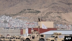 FILE - Armored vehicles with the Taliban flags are parked inside a deserted US military camp at the airport in Kabul, Sept.14, 2021. 