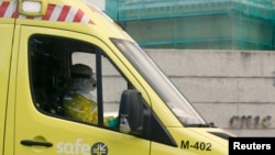 An ambulance driver in protective suit arrives at Madrid's Carlos III Hospital carrying a possible new Ebola patient, in Madrid, Oct. 16, 2014. 