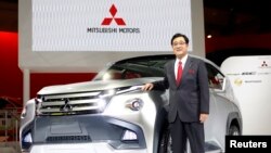 Presiden Mitsubishi Motors Corp Osamu Masuko berfoto dekat mobil konsep GC-PHEV pada Tokyo Motor Show, November 2013. 