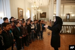 A museum guide Zeinab Sadat Asadi explains for schoolboys as they visit Niavaran Palace, now a museum, that was the primary and last residence of late shah.