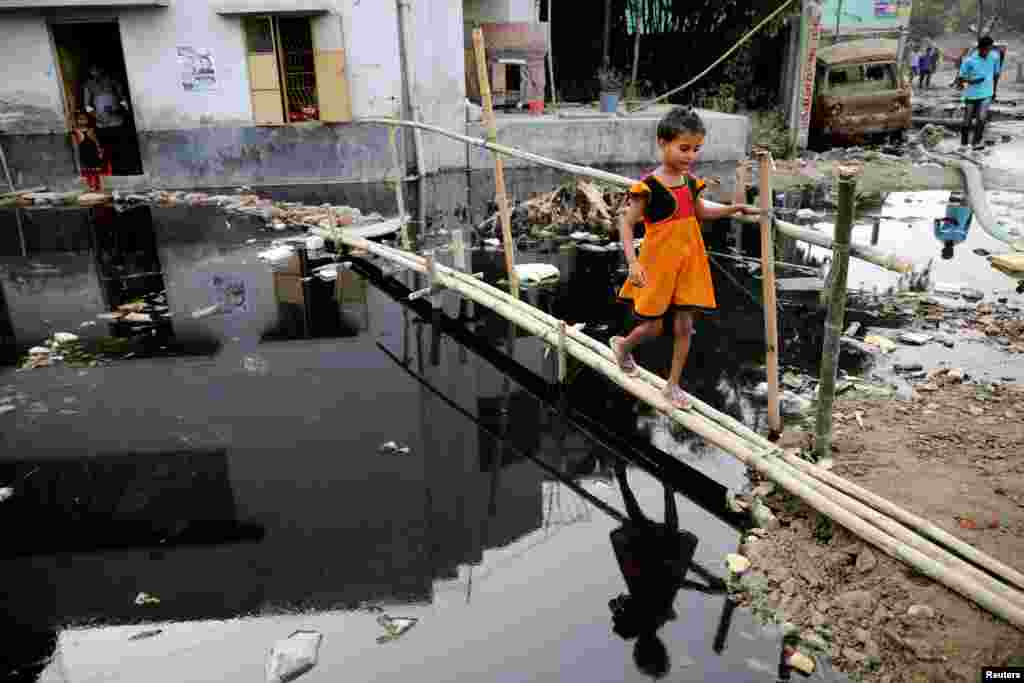 A girl walks over a bamboo bridge in front a house in Dhaka, Bangladesh.