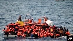 In this photo released by Doctors Without Borders, an overcrowded wooden boat packed with 99 migrants is approached by a tender of the humanitarian organization off the Libya coast on Nov. 16, 2021.
