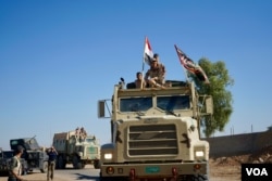 Iraqi troops move further into Mosul. Some army vehicles sported Shi’ite banners in addition to the Iraqi national flag, Nov. 3, 2016. (Photo: Jamie Dettmer for VOA)