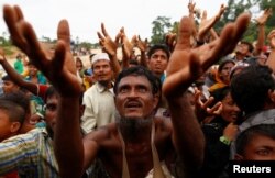 Rohingya refugees stretch their hands to receive food distributed by local organizations in Kutupalong, Bangladesh, Sept. 9, 2017.