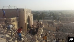 FILE - In this July 24, 2014 file photo, people walk on the rubble of the destroyed Mosque of The Prophet Younis, or Jonah, in Mosul, 225 miles (360 kilometers) northwest of Baghdad, Iraq. 