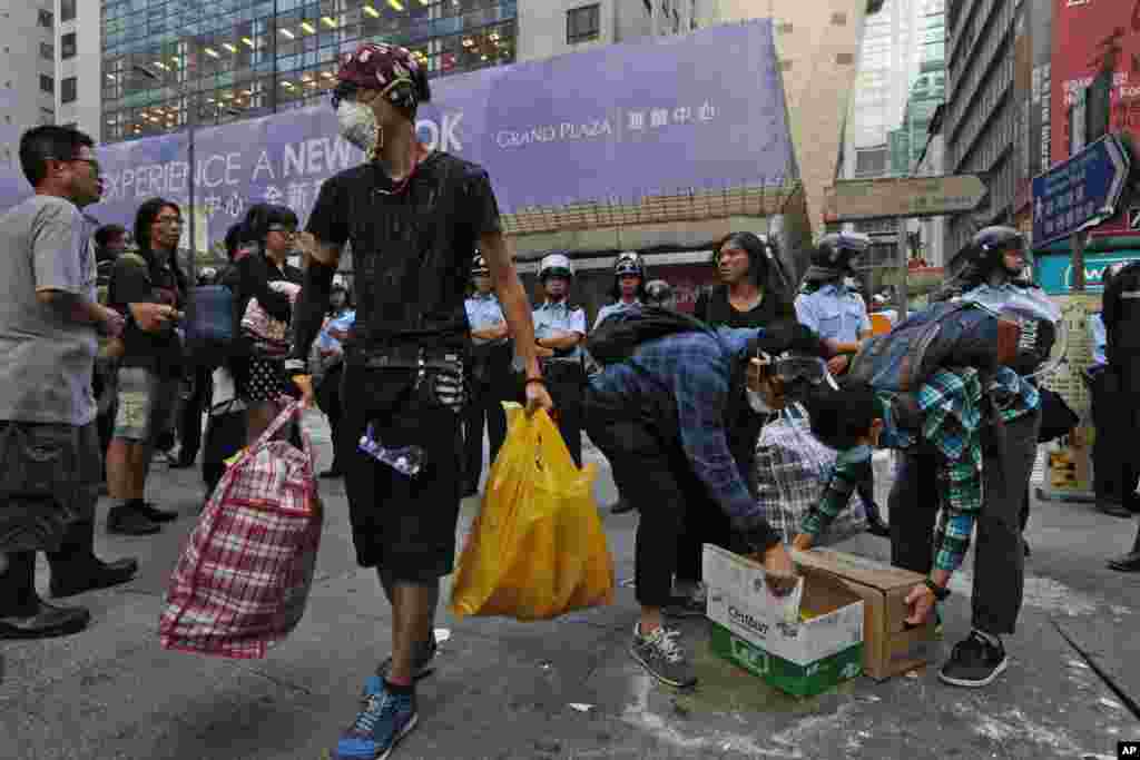 Pro-democracy protesters remove their belongings as riot police clear their encampment in the occupied area in the Mong Kok district of Hong Kong, early Friday, Oct. 17, 2014.