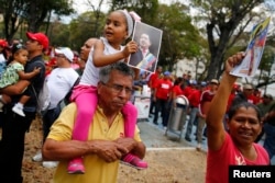 A girls taking part in a demonstration supporting Venezuela's President Nicolas Maduro's holds a picture of late president Hugo Chavez during a rally with Bolivarian militia in Caracas March 15, 2014. REUTERS/Jorge Silva