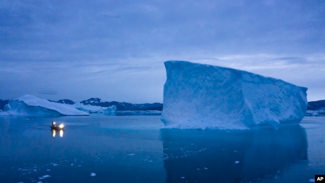 In this Aug. 15, 2019, file photo, a boat navigates at night next to large icebergs in eastern Greenland. (AP Photo/Felipe Dana, File)
