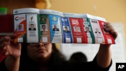 Un assesseur exhibe un bulletin de vote au nom du président Evo Morales après la fermeture des bureaux de vote à La Paz, en Bolivie, le dimanche 20 octobre 2019. (AP Photo / Juan Karita)