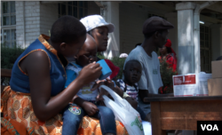 Officials force a child suspected of having contracting cholera to take an oral rehydrating solution at a temporary treatment center in Harare, Sept. 11, 2018. (C. Mavhunga/VOA)