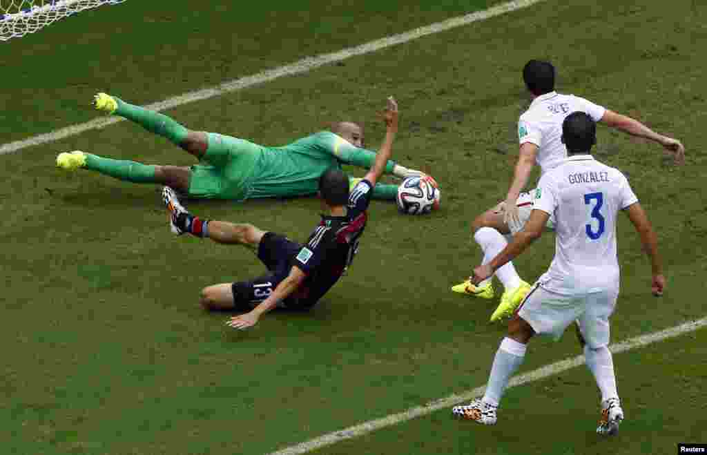 Goalkeeper Tim Howard of the U.S. makes a save as Germany&#39;s Thomas Mueller looks on at the Pernambuco arena in Recife, June 26, 2014. 