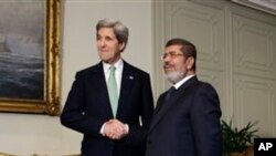 Menlu AS John Kerry (kiri) berjabat tangan dengan Presiden Mesir Mohamed Morsi di Istana Kepresidenan Mesir di Kairo (3/3).