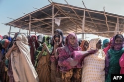 FILE - People gather to receive food at a distribution site in Farbudo, a camp for internally displaced people, in Gode, near Kebri Dahar, southeastern Ethiopia, Jan. 27, 2018. Nearly a million people have been displaced in southern Ethiopia due to ethnic violence.