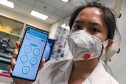 Seorang peneliti dari Universitas Teknologi Nanyang mengenakan masker pintar yang terhubung dengan aplikasi di teleponnya melalui teknologi Bluetooth., 16 September 2020. (Foto: dok).