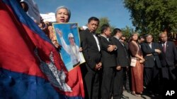 A supporter of the opposition Cambodia National Rescue Party holds a poster of the party leader Kem Sokha during a rally joined by lawmakers near an appeals court in Phnom Penh, Cambodia, Tuesday, Sept. 26, 2017. The court rejected a request for the release on bail of opposition leader Kem Sokha, who has been charged with treason in a case that is seen as a partisan political effort by the government ahead of next year's general election. (AP Photo/Heng Sinith)