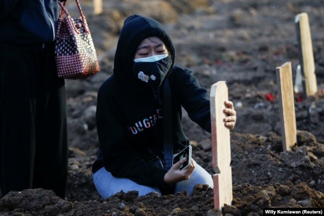 Seorang gadis berduka usai pemakaman ayahnya yang berusia 56 tahun yang meninggal karena COVID-19, di area pemakaman yang disediakan pemerintah untuk korban COVID-19, di Jakarta, 28 Juni 2021.(Foto: REUTERS/ Willy Kurniawan)