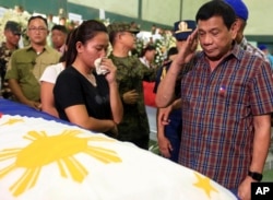 FILE - Philippine President Duterte salutes flag-draped coffins of 15 soldiers killed in a gun battle with Muslim Abu Sayyaf militants during his visit to Western Mindanao Command in Zamboanga city, southern Philippines, Aug. 31, 2016