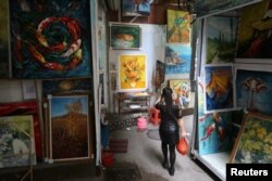 Seorang wanita melintas di gang yang dikelilingi oleh lukisan-lukisan di dinding di Desa Lukisan Minyak Dafen di Shenzhen, provinsi Guangdong, China, 5 Desember 2018 (foto: Reuters/Thomas Suen)
