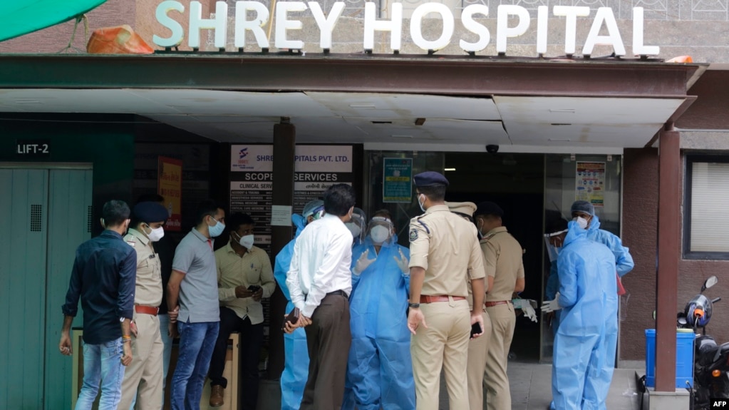 Petugas forensik, mengenakan alat pelindung diri, berbicara dengan polisi dan pejabat pemerintah di rumah sakit Shrey, di Ahmedabad, India, pasca kebakaran, Kamis, 6 Agustus 2020. 