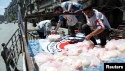Syrian Arab Red Crescent members place a red crescent flag on top of a food aid truck before moving it to Aleppo Central Prison, May 11, 2014. 