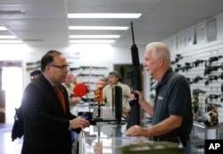 FILE - Sales associate Mike Conway, right, shows Paul Angulo a semiautomatic rifle at Bullseye Sport gun shop in Riverside, Calif., Dec. 9, 2015.