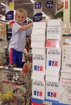 FILE - A schoolboy stands near a pile of "Le Petit Robert" dictionaries in a supermarket in Marseille on Aug. 26, 1999, a few days before the start of the school year.