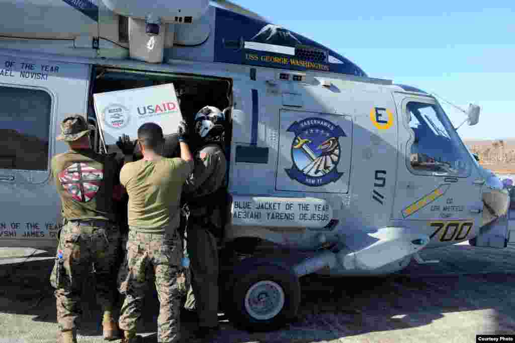 U.S. Marines help load relief supplies onto an MH-60R Seahawk to be airlifted to remote areas of the Philippines in support of Operation Damayan. (U.S. Navy)