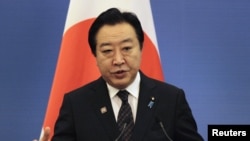 Japan's Prime Minister Yoshihiko Noda gestures in front of a Japanese national flag as he speaks at a joint news conference, May 13, 2012.